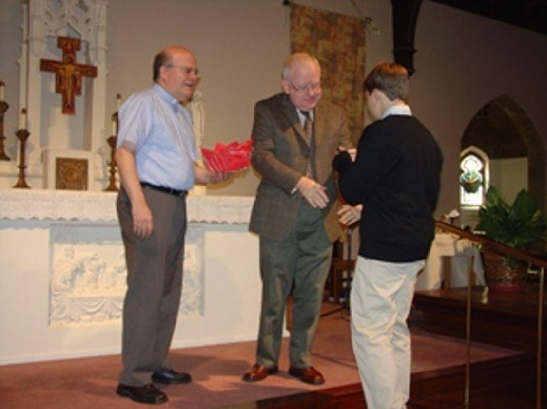 Holy Spirit School Photo - Eighth Graders accept Holy Spirit pins, signifying their acceptance of their role as school leaders. On the altar is Father Joe O'Brien and presenting the pin is principal, Roger Rooney.