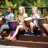 Greensboro Montessori School Photo #8 - Third graders play djembe drums for an outdoor assembly. Elementary students take weekly lessons in world music and visual arts.