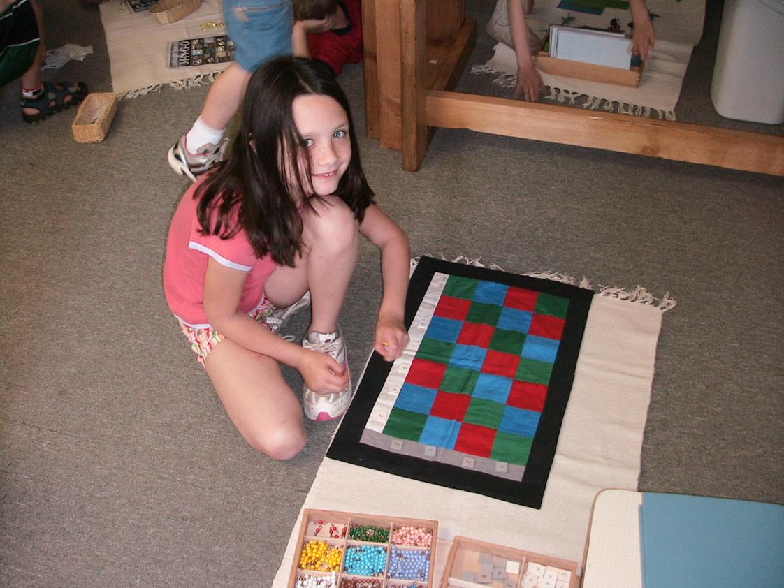 Pinewoods Montessori Schoolcorp Photo - An elementary student doing her math work using Montessori materials. The Montessori math curriculum includes using concrete methods of learning abstract concepts.