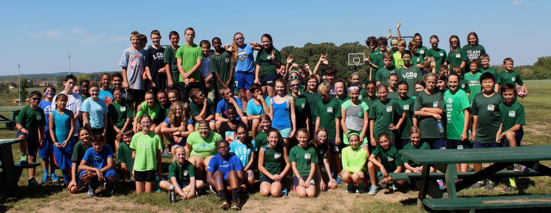 Loudoun Country Day School Photo - Middle school students participate in the traditional Blue and Green Games in September after bonding in a week of activities, including using zip lines, rock climbing, and river rafting. The middle school is divided between blue and green teams throughout the year. Here they pose together after a day of outside activities.