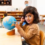Montessori De Terra Linda Photo #4 - A three year old learns about land and water on the Sandpaper Globe in the Primary class.