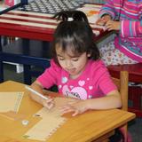 The Happy Childrens Montessori Photo #1 - This girl is concentrating hard on her number papers. She is 4.