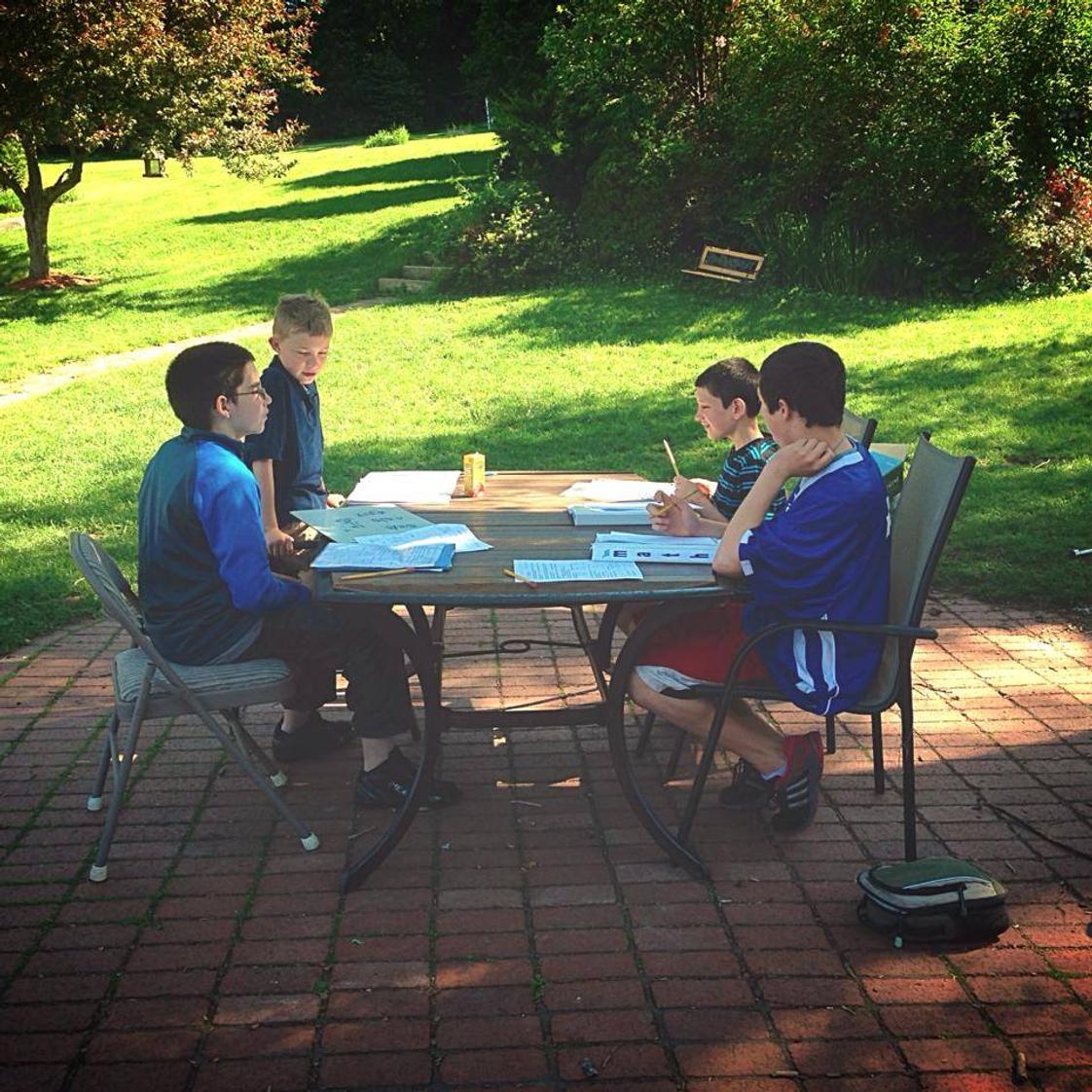 Plumfield Academy Photo - These boys are taking advantage of a sunny day to work on their math outside. Sometimes the cool breeze is enough motivation!