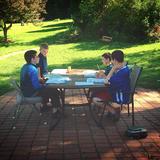 Plumfield Academy Photo #2 - These boys are taking advantage of a sunny day to work on their math outside. Sometimes the cool breeze is enough motivation!