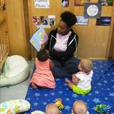 Hampton KinderCare Photo #3 - Ms. Bianca shares her love of reading with a group of eager infants. They all love nursery rhymes!