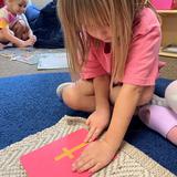 Christian Montessori Academy Photo #9 - A student traces over a sandpaper letter to practice the initial sounds and pre-writing in Children's House.