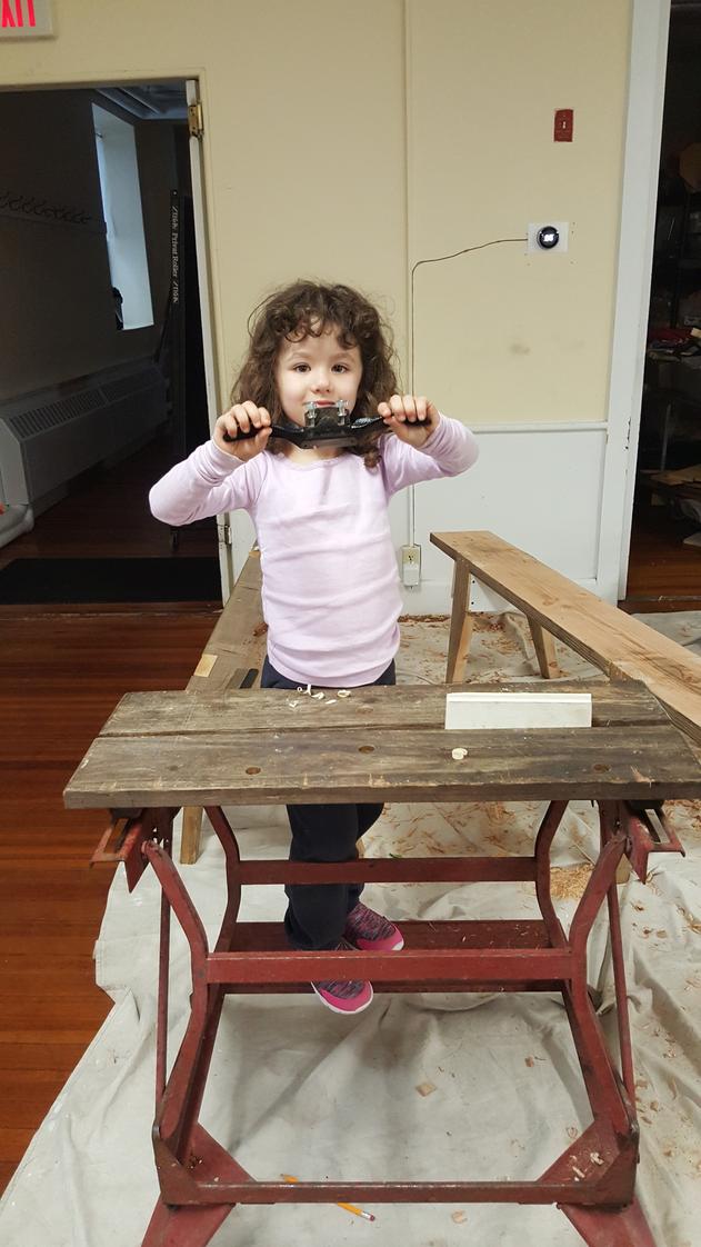 Longview School Photo #1 - Our youngest student, 4 year old Maizie, is sanding their collaborative woodworking project.