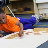 Greenspring Montessori School Photo #3 - A Children's House student does addition into the hundreds with this Montessori material.