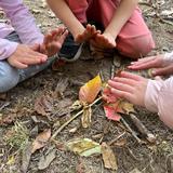 City Garden School Photo #4 - Embracing the warmth and simplicity of play, these hands find comfort in an imaginary fire made of twigs and autumn leaves.