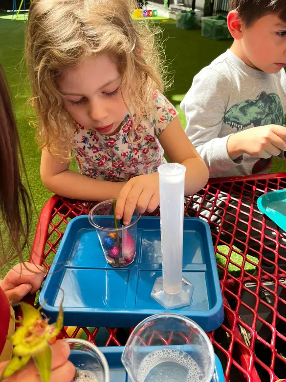 International Children's Academy Photo - Bubble, bubble, toil and trouble... we're mixing up a special potion using flower petals, shells, beads, and all sorts of materials. We're learning how to share and create all at the same time.