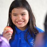 Lake Rose Christian Academy Photo #17 - A Lake Rose Christian Academy student smiles during a classroom moment, holding a fresh apple as she interacts with others.