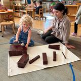 Near North Montessori Photo - An engaged learner in our Primary Class for children ages 3 years to 6 years, is receiving a lesson with a Montessori material known as the brown stair. The brown stair helps children develop their awareness of size differences