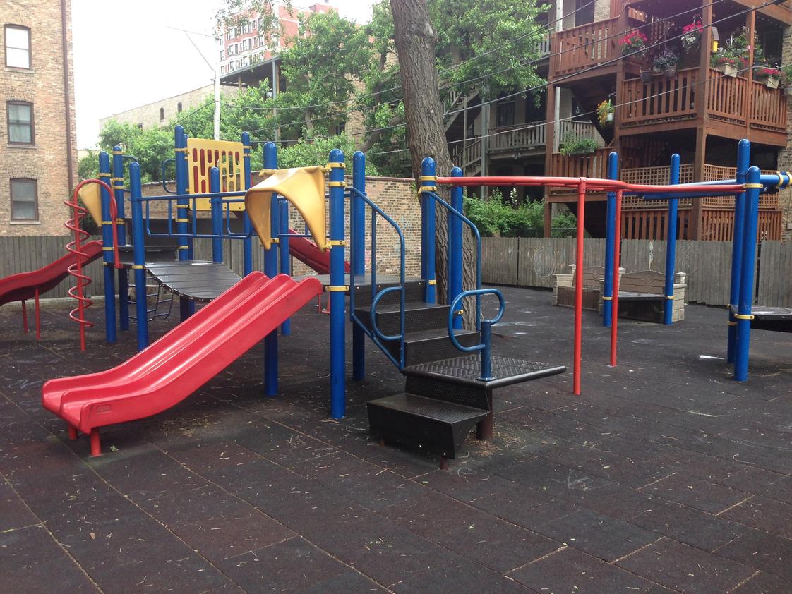 Park View Montessori School - Chicago Photo #1 - We have a large outdoor playground with many beautiful trees, a large metal play structure, and three smaller play structures along with a climbing wall.