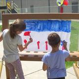 East Riverside KinderCare Photo #7 - Our school-age children develop fine motor skills and explore their creativity while painting on the playround